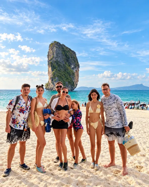 Group of guests on the beach at Poda Island, with a limestone rock behind