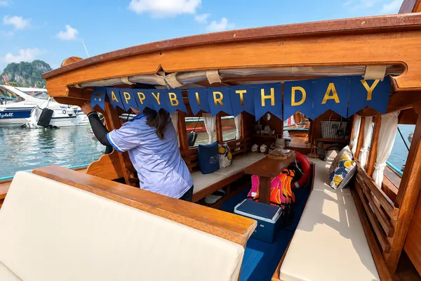 Crew member hanging a Happy Birthday banner across the boat cabin