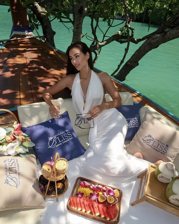 Picnic set up on the deck of a Krabi Bliss longtail boat — branded cushions, fruit platter and fresh coconut
